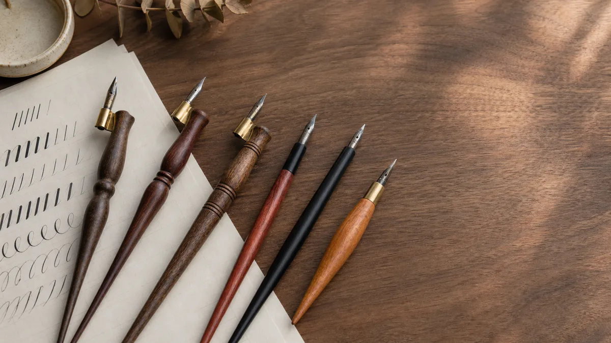 Selection of straight and oblique calligraphy pen holders on a wooden desk.