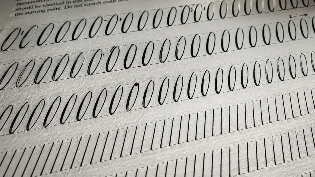 Macro close-up of perfectly repeated oval and hairline stroke drills on a calligraphy practice sheet