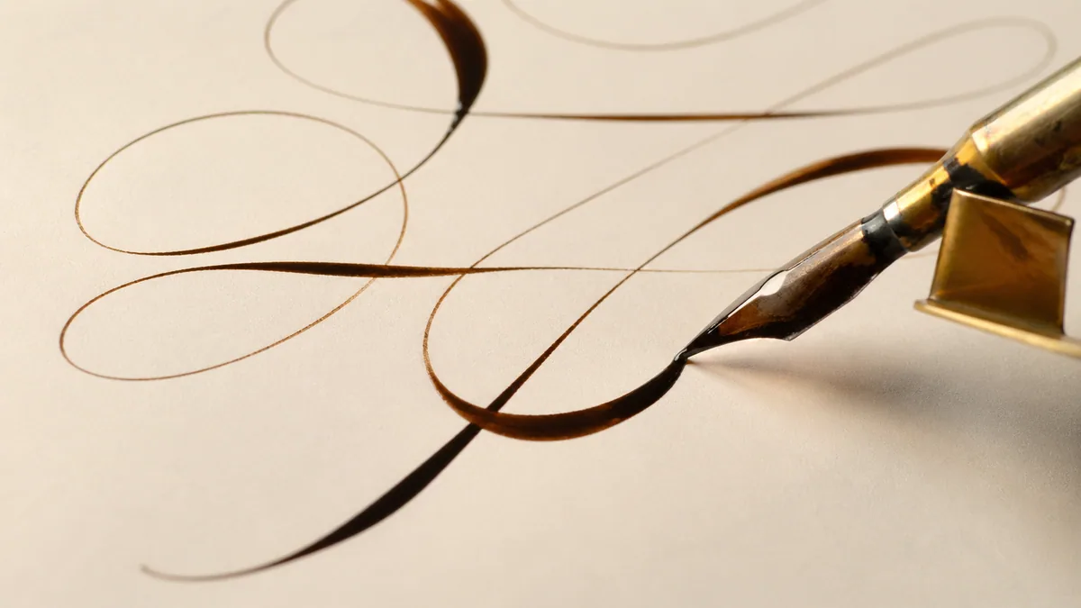 Macro close-up of a Copperplate flourish executed with a pointed nib in an oblique holder